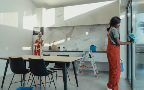 Professional cleaners in overalls cleaning a bright modern kitchen