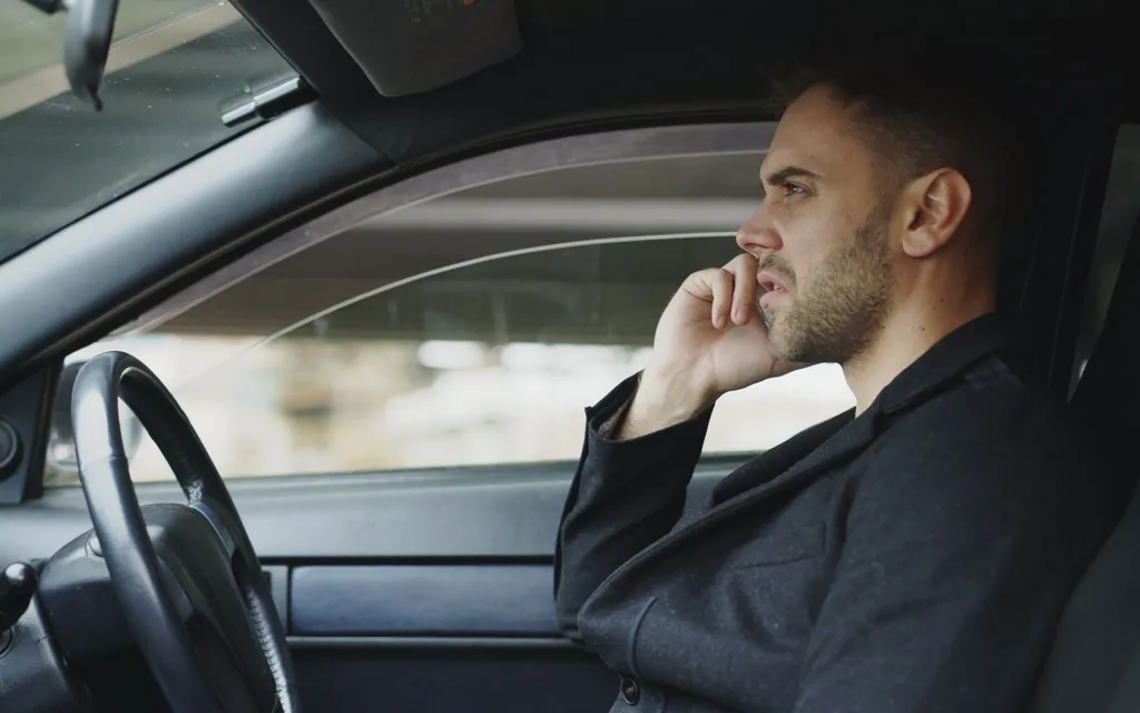 Driving instructor in the driver's seat of a car taking a call on his phone