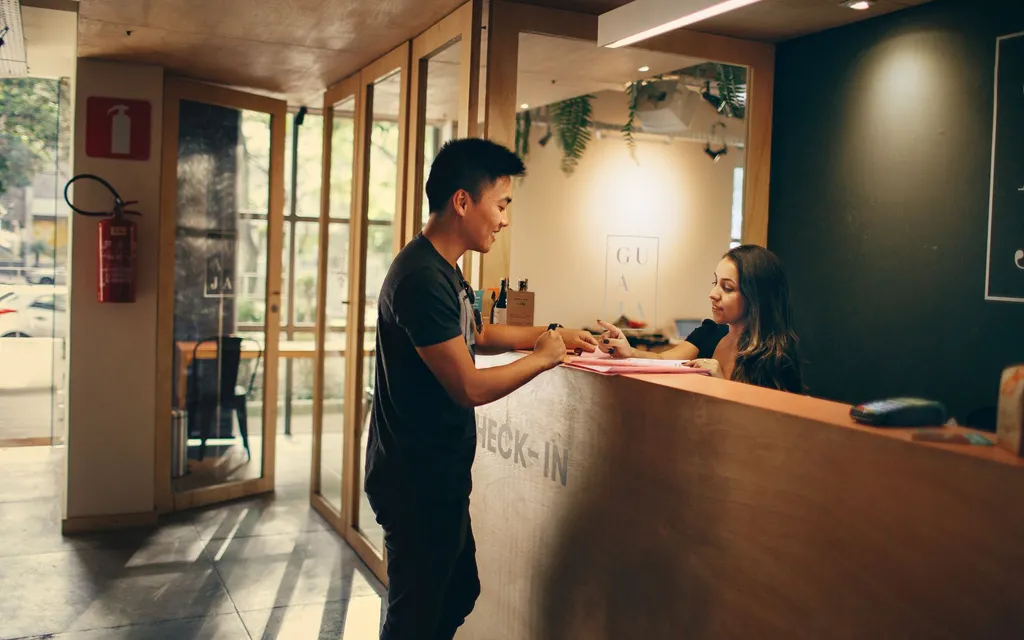 A guest checking in with a smiling receptionist at the front desk of a modern hotel
