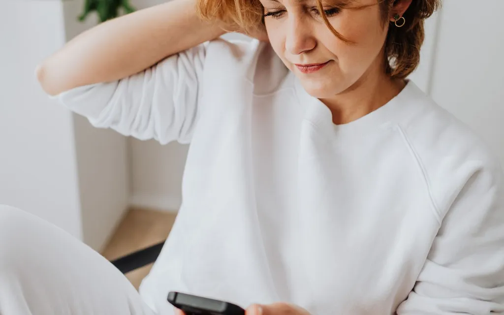 A woman in a white top using her mobile phone