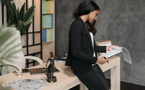 Solicitor in a dark suit reviewing legal documents beside a Lady Justice statuette